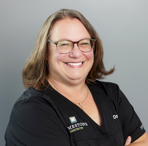 Smiling woman on the phone at the front desk of a dental practice