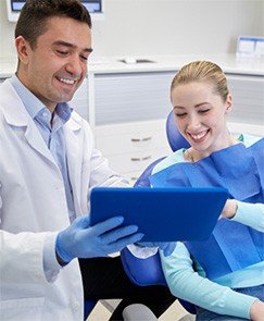 Jeffersonville cosmetic dentist and smiling patient reviewing a clipbaord