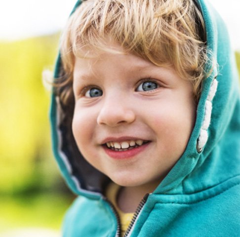 young child in blue hoody smiling outside