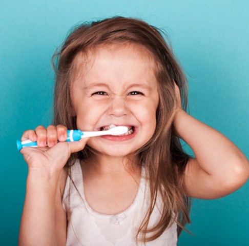 smiling little girl brushing her teeth with dye-free toothpaste in Jeffersonville 
