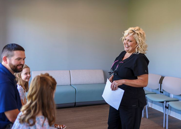 Smiling woman in dental chair talking to team member