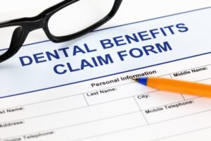 Glasses and pen atop Dental Benefits Claim Form paperwork